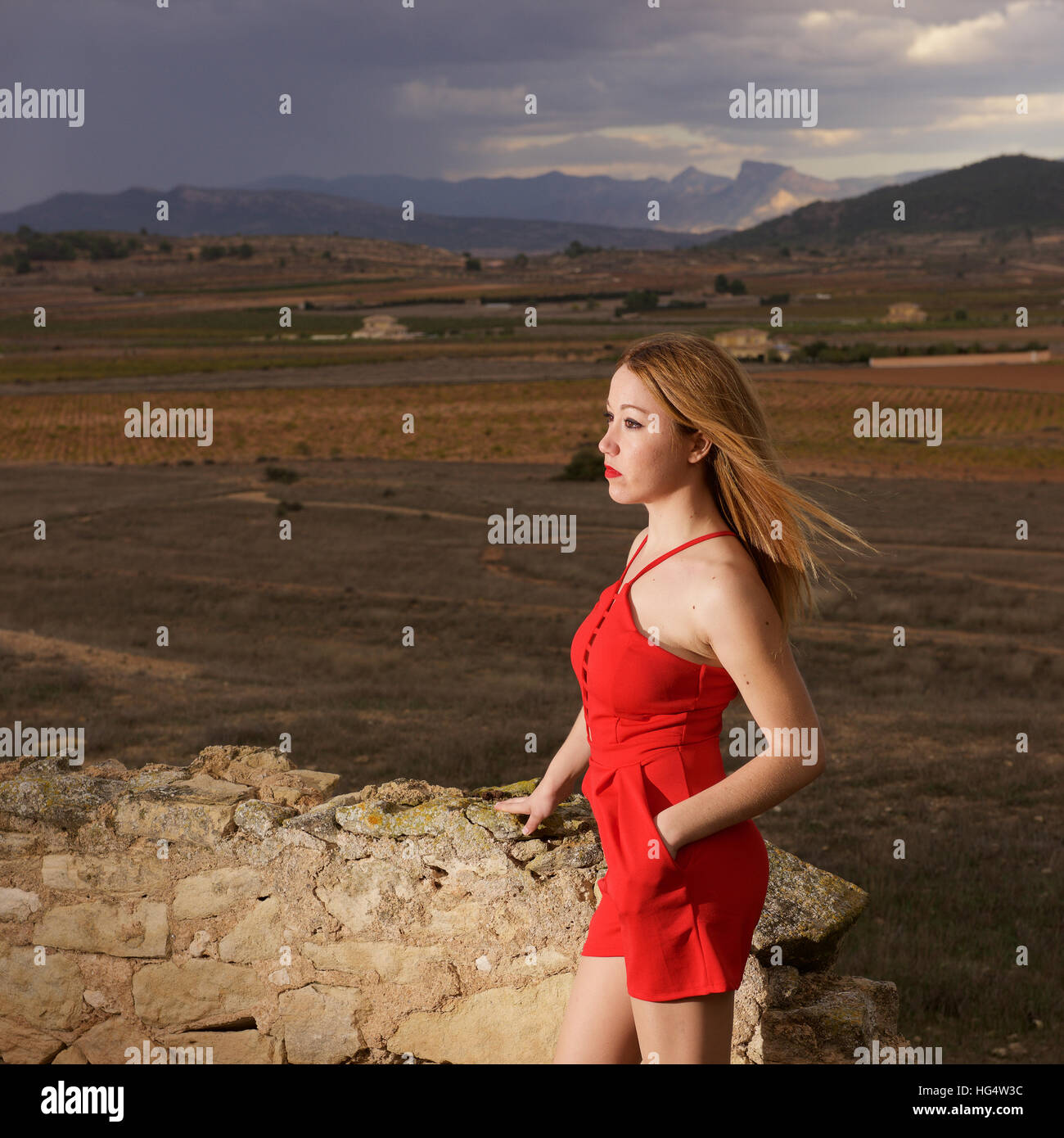Hübsche junge Frau mit langen blonden Haaren kurz rot Outfit mit high Heels. Im Freien bei Gewitter. Stockfoto