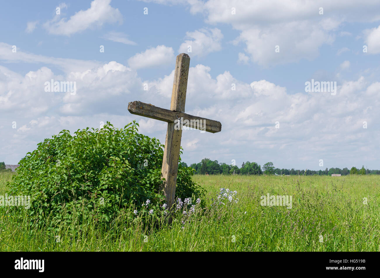 alten verwitterten hölzernen katholische Kreuz auf der grünen Wiese Stockfoto