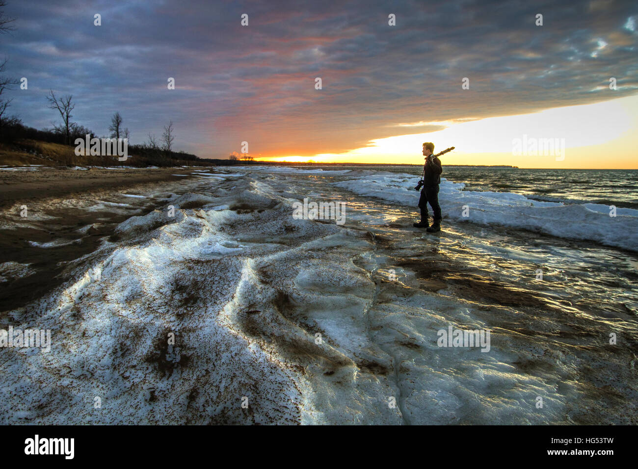 Fotograf, stehend auf einem zugefrorenen See.  Männlichen Fotografen auf der gefrorenen Küste von Michigan Great Lakes Strand stehen. Stockfoto
