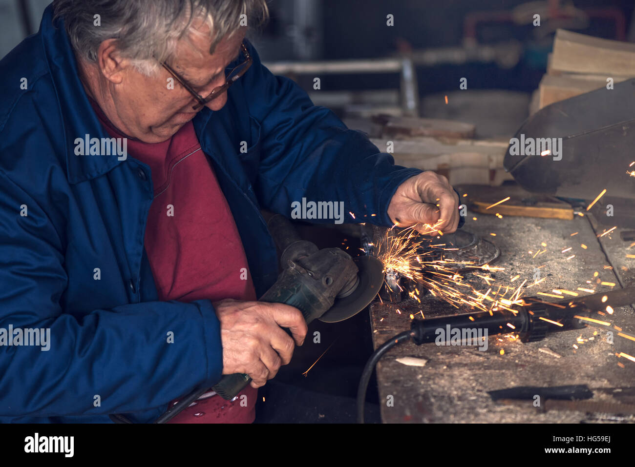 Reifen männlichen Arbeitnehmer Schleifen Stück Metall mit Mahlwerk Werkzeug in Werkstatt ohne Schutzausrüstung Stockfoto