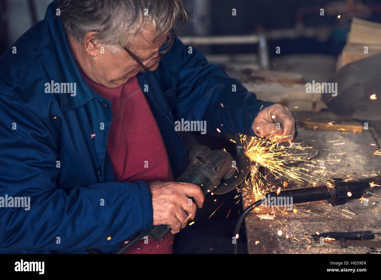 Reifen männlichen Arbeitnehmer Schleifen Stück Metall mit Mahlwerk Werkzeug in Werkstatt ohne Schutzausrüstung Stockfoto
