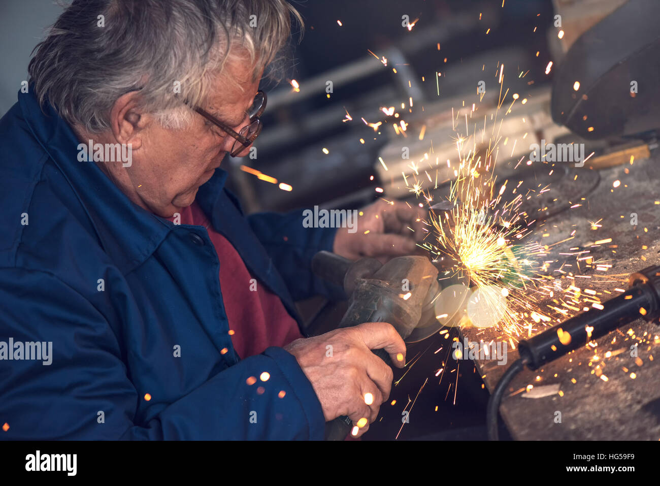 Reifen männlichen Arbeitnehmer Schleifen Stück Metall mit Mahlwerk Werkzeug in Werkstatt ohne Schutzausrüstung Stockfoto