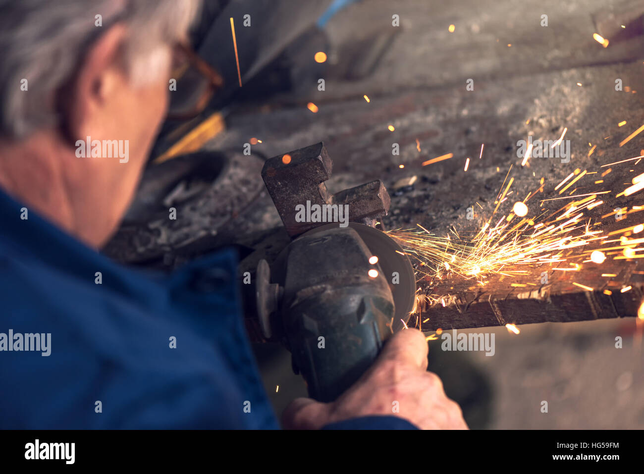 Reifen männlichen Arbeitnehmer Schleifen Stück Metall mit Mahlwerk Werkzeug in Werkstatt ohne Schutzausrüstung Stockfoto