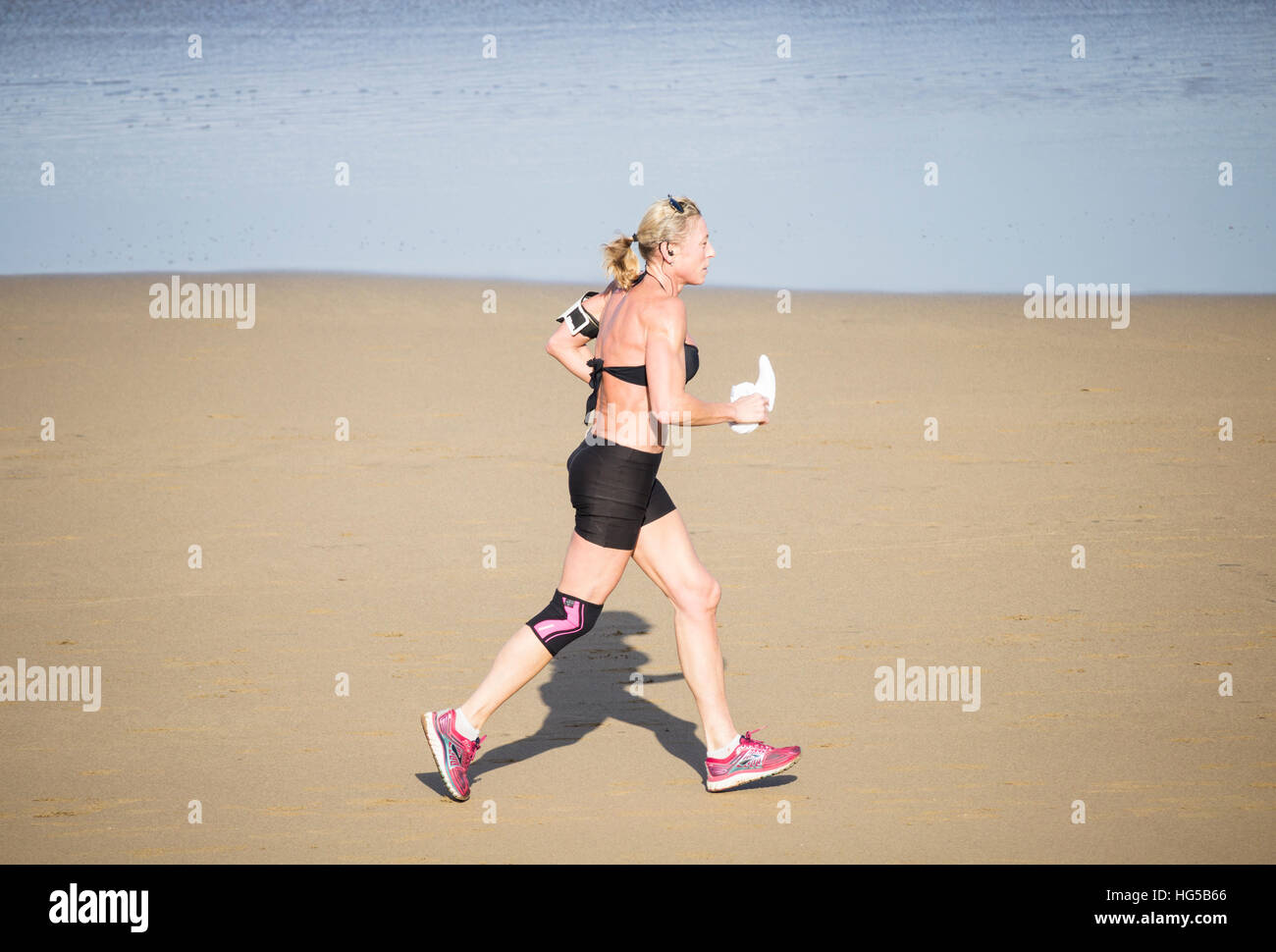 Reife Frau am Strand laufen. Stockfoto