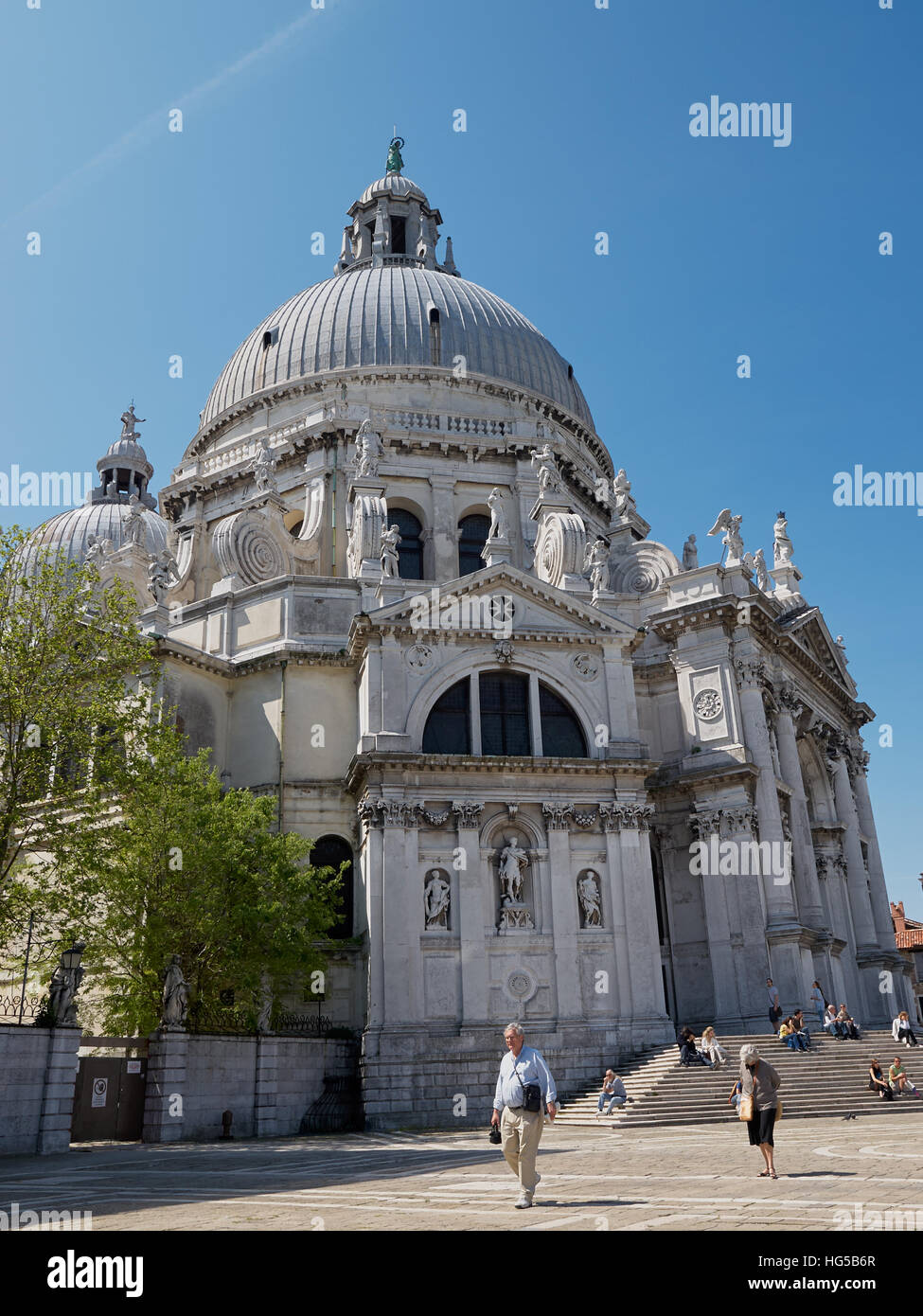 Basilica di Santa Maria della Salute in Venedig, Italien, mit Touristen, die sich in der Frühlingssonne entspannen. Stockfoto