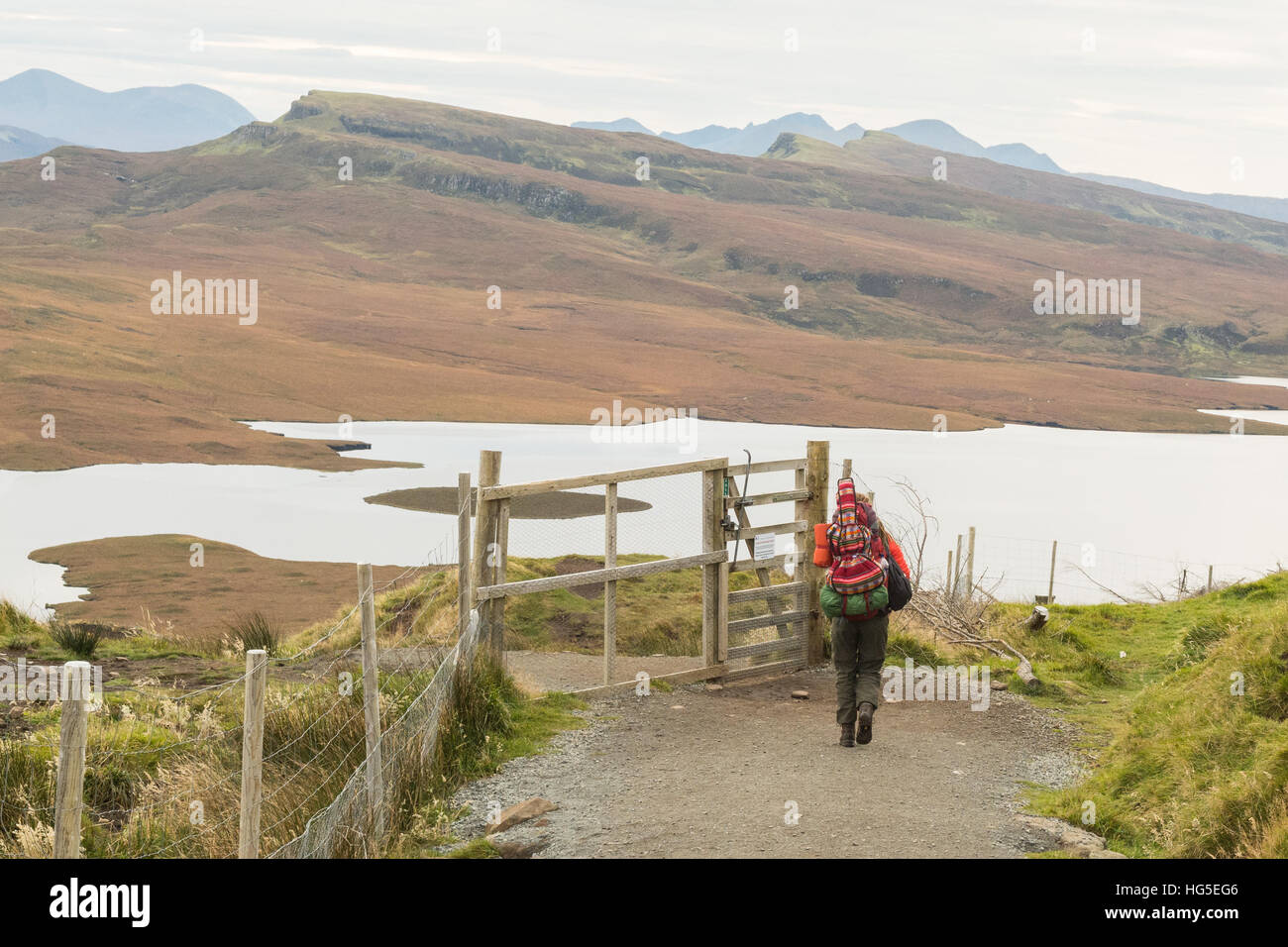 einsame Wanderer weiblichen Reisenden mit Gitarre auf Rücken absteigend von der Old Man of Storr, Isle Of Skye, Schottland im Herbst Stockfoto