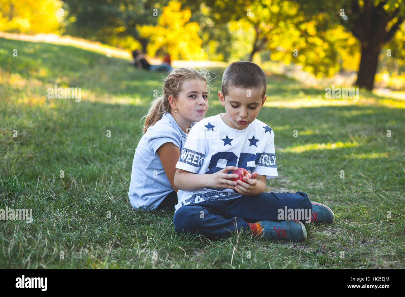 Kinder Jungen und Mädchen Verzehr von Äpfeln im Park auf dem Rasen Stockfoto