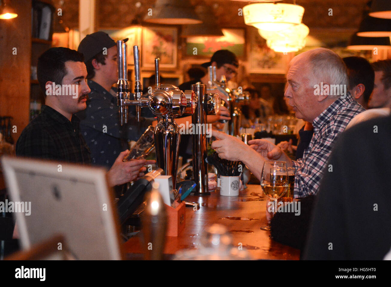 Eine Person bestellt ein alkoholisches Getränk bei einem Barkeeper in einem Pub oder Restaurant. Stockfoto