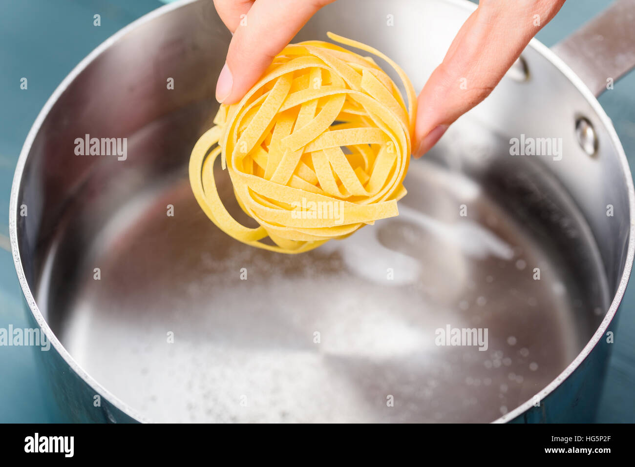 Hinzufügen von Tagliatelle Nudeln In heißem Wassertopf zum Kochen Stockfoto