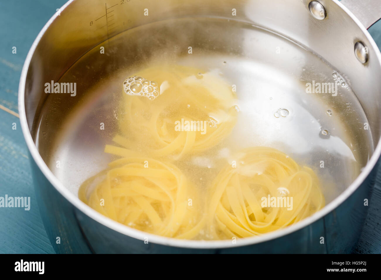 Hinzufügen von Tagliatelle Nudeln In heißem Wassertopf zum Kochen Stockfoto