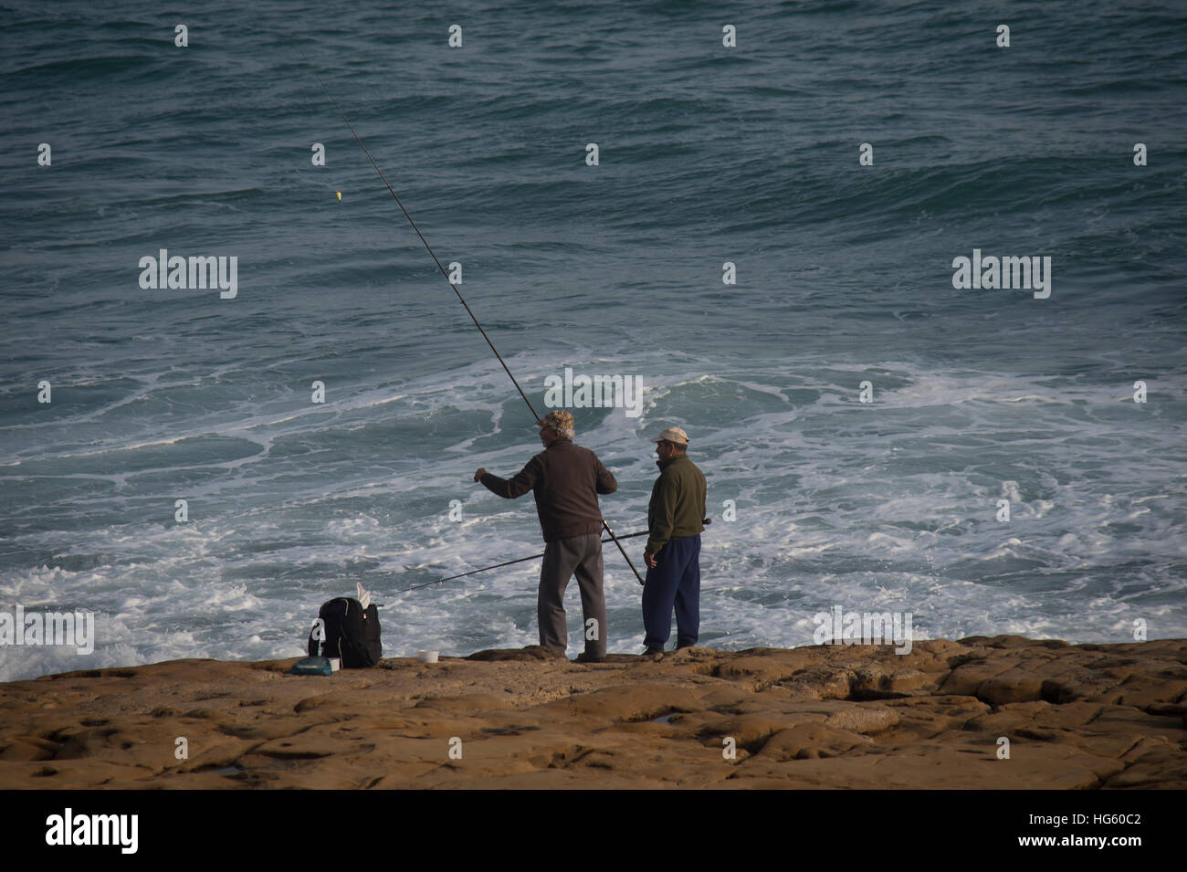zwei Männer, die von den Felsen in Luz Portugal Angeln Stockfoto