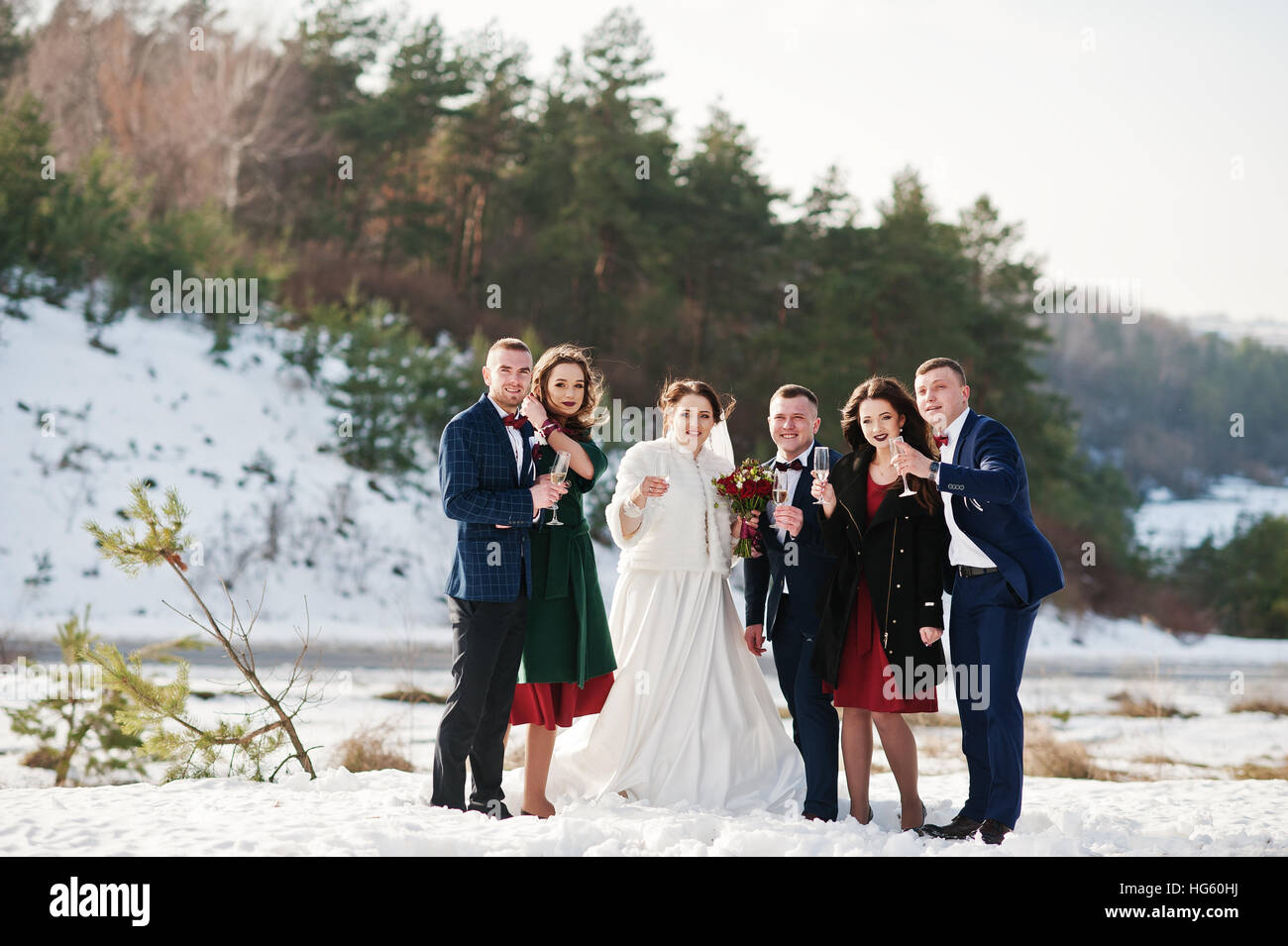 Trauzeuge mit Brautjungfern und Brautpaar trinken Champagner auf Frost-Winter-Hochzeit. Stockfoto
