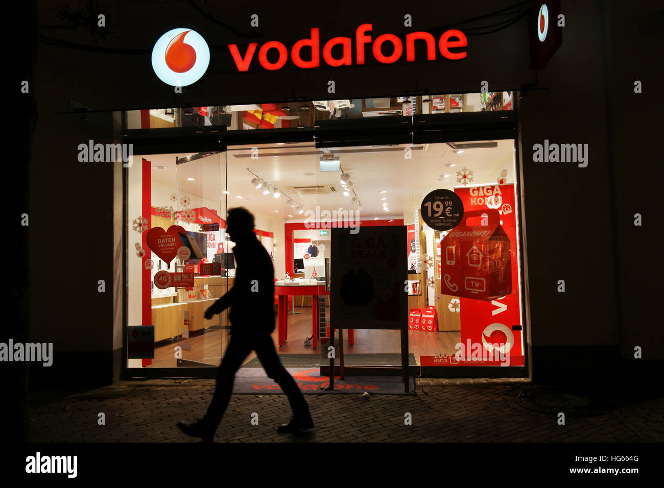 Silhouette der Mann er Nacht ein Vodafone-Telekommunikation-Shop vorbei. Stockfoto