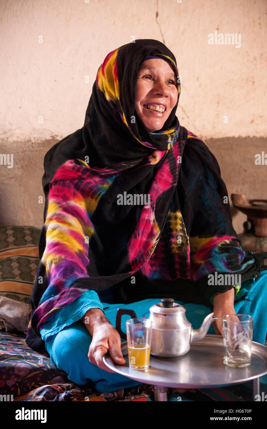 Ksar Elkhorbat, Marokko.  Mittleren Alters Amazigh Berber Frau trinken Tee in ihrem Wohnzimmer. Stockfoto