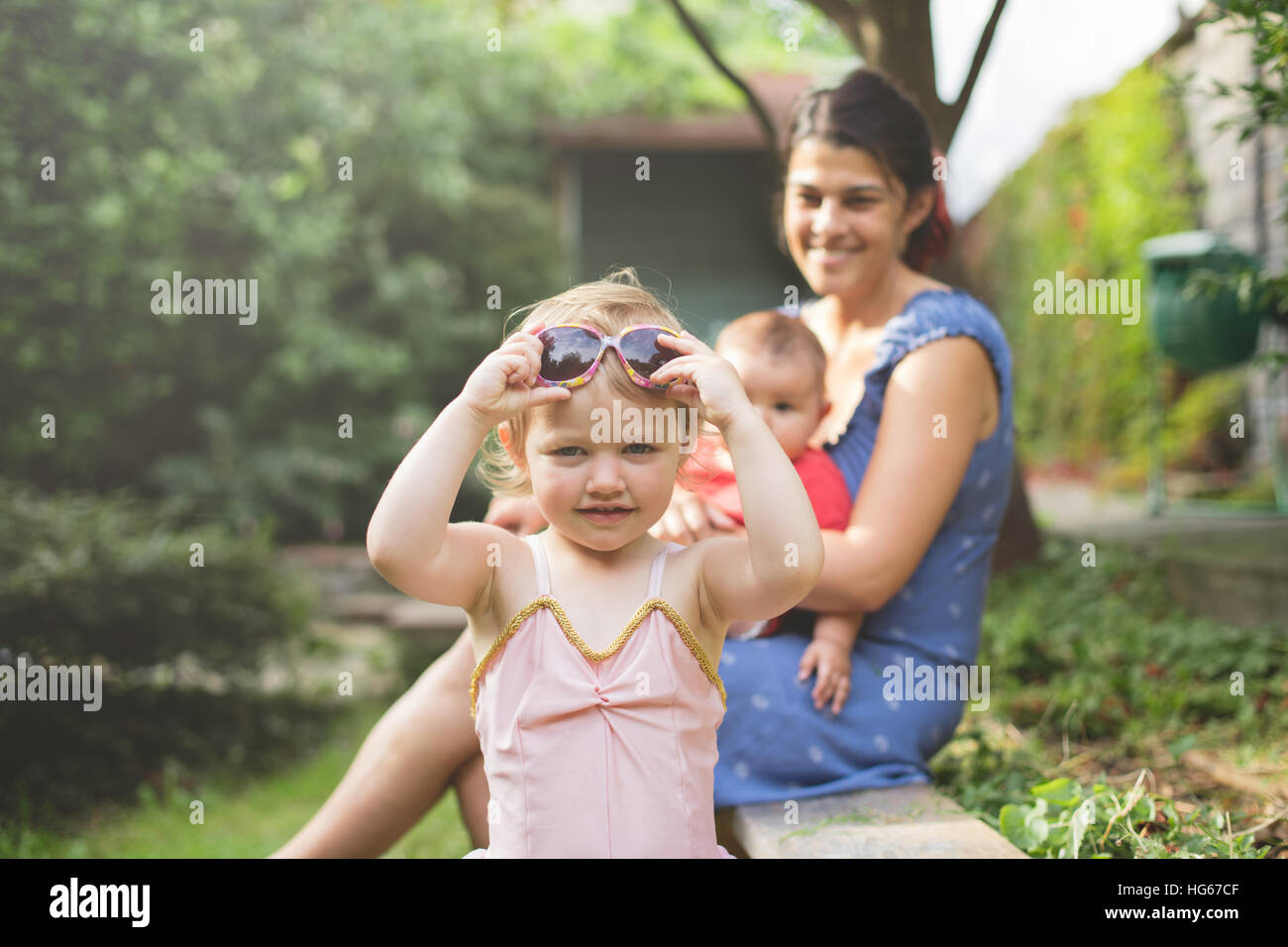 Porträt einer jungen Tochter, die ihre Mütter Sonnenbrille im Garten hautnah Stockfoto