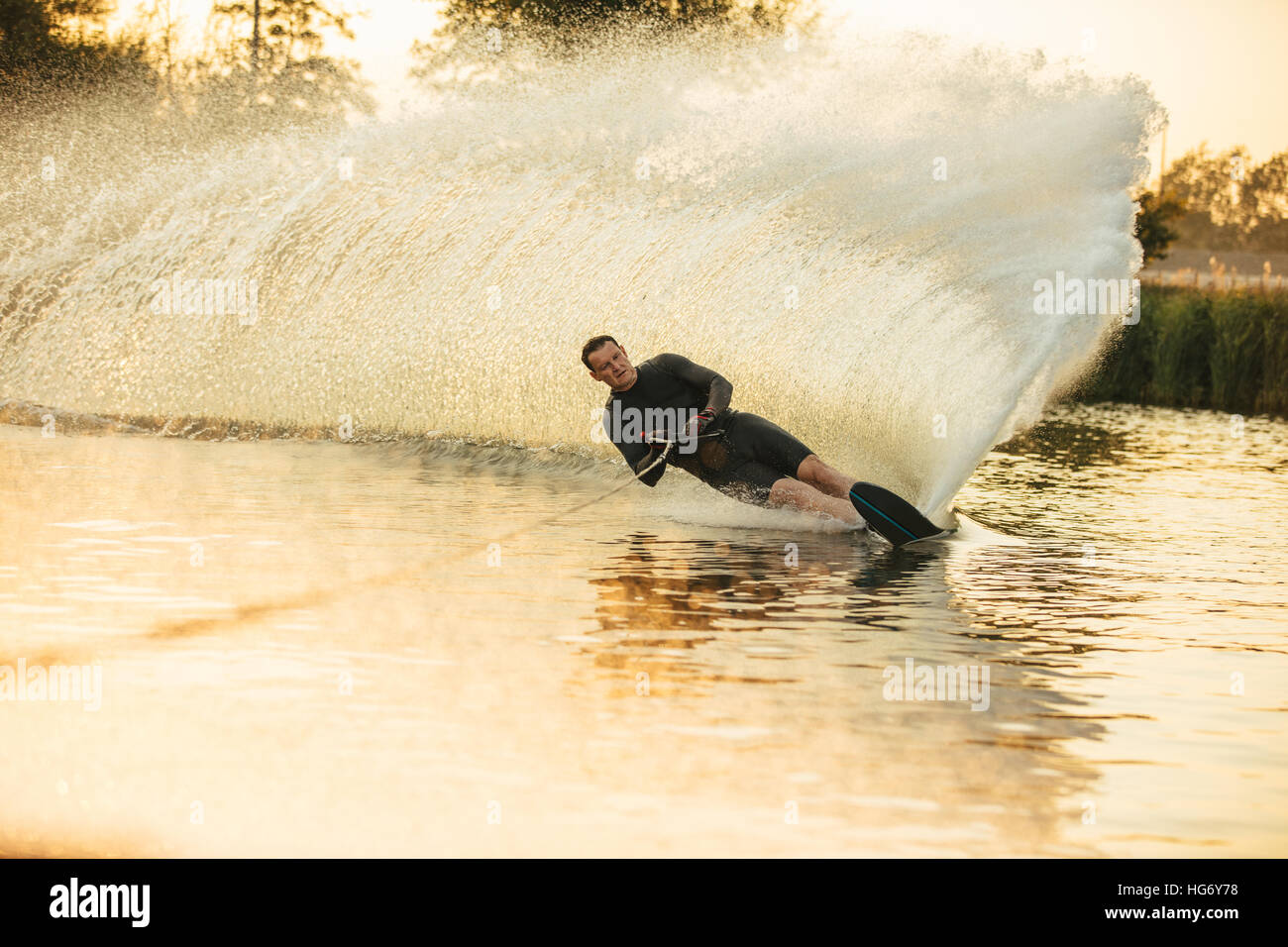 Mann Wakeboarden an einem See mit Spritzer Wasser. Wakeboarder Surfen über den See Angeberei ist Fertigkeit. Stockfoto