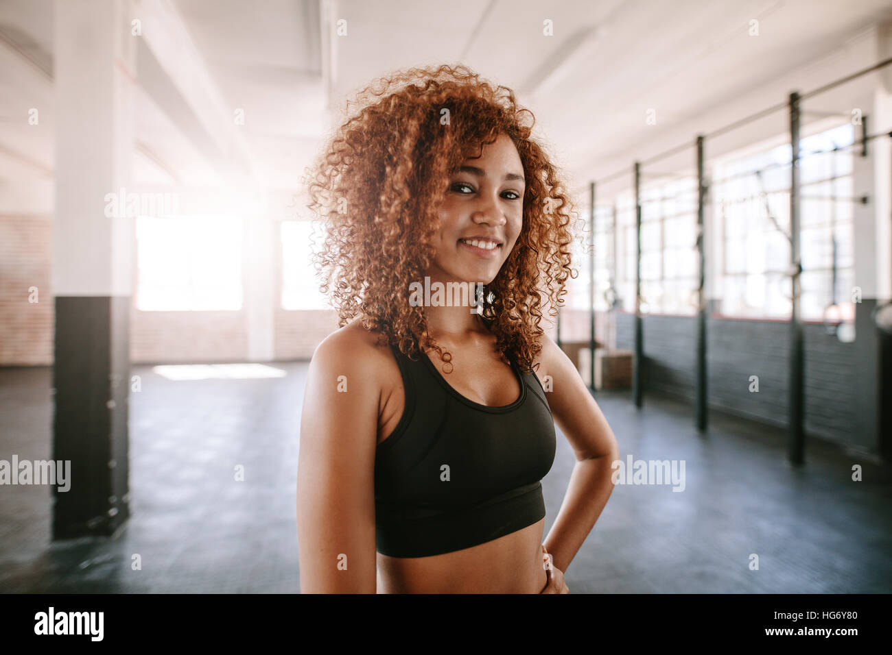 Porträt der lächelnde junge afrikanische Frau mit lockigen Haaren im Health Club. Glücklich und schön Fitness-Frau im Fitnessstudio. Stockfoto