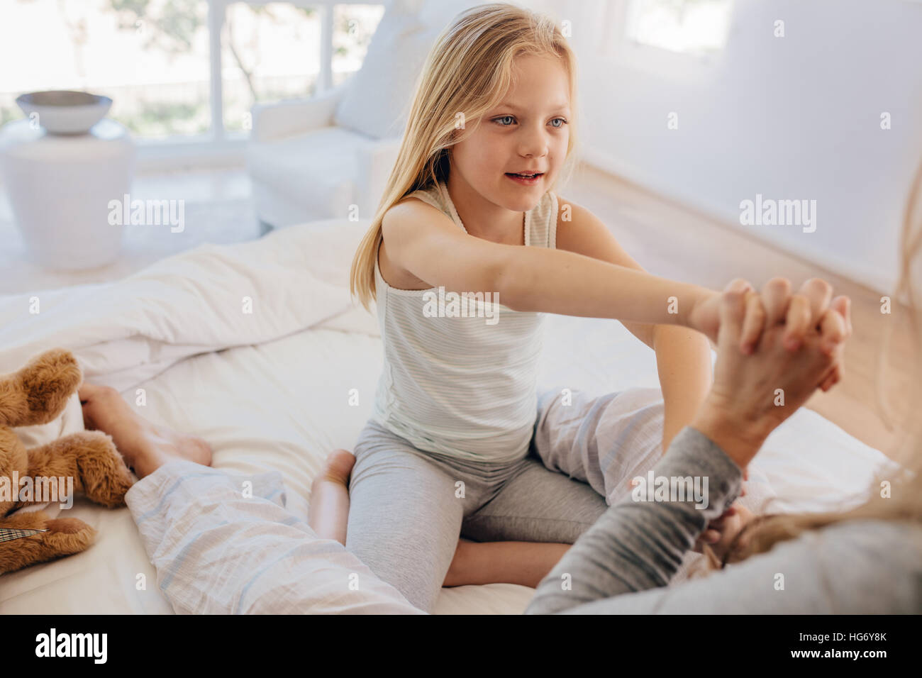 Schöne kleine Mädchen mit ihrer Mutter am Bett. Niedliche Tochter mit ihrer Mutter im Schlafzimmer spielen. Stockfoto