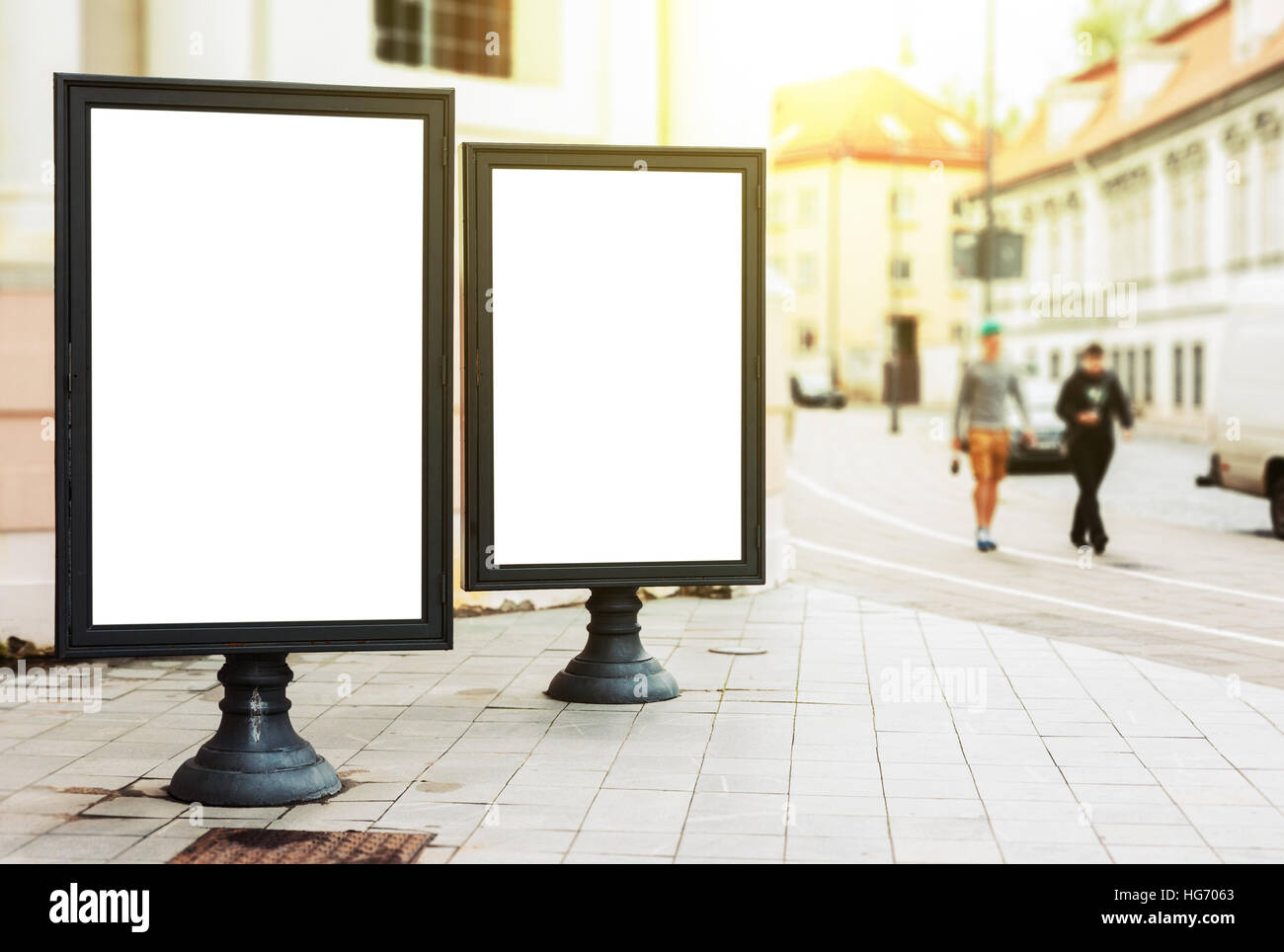 Zwei leere Werbetafeln auf der Stadtstraße mit Fußgängern und Sonne glühen Stockfoto