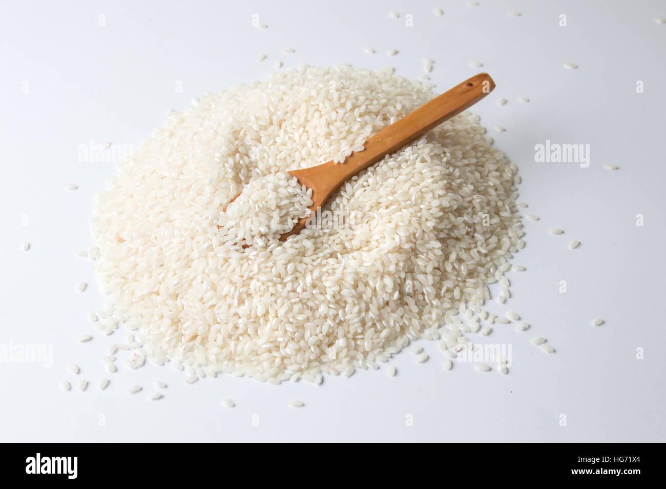 Holzlöffel in Haufen von Reis auf weißem Hintergrund Stockfoto