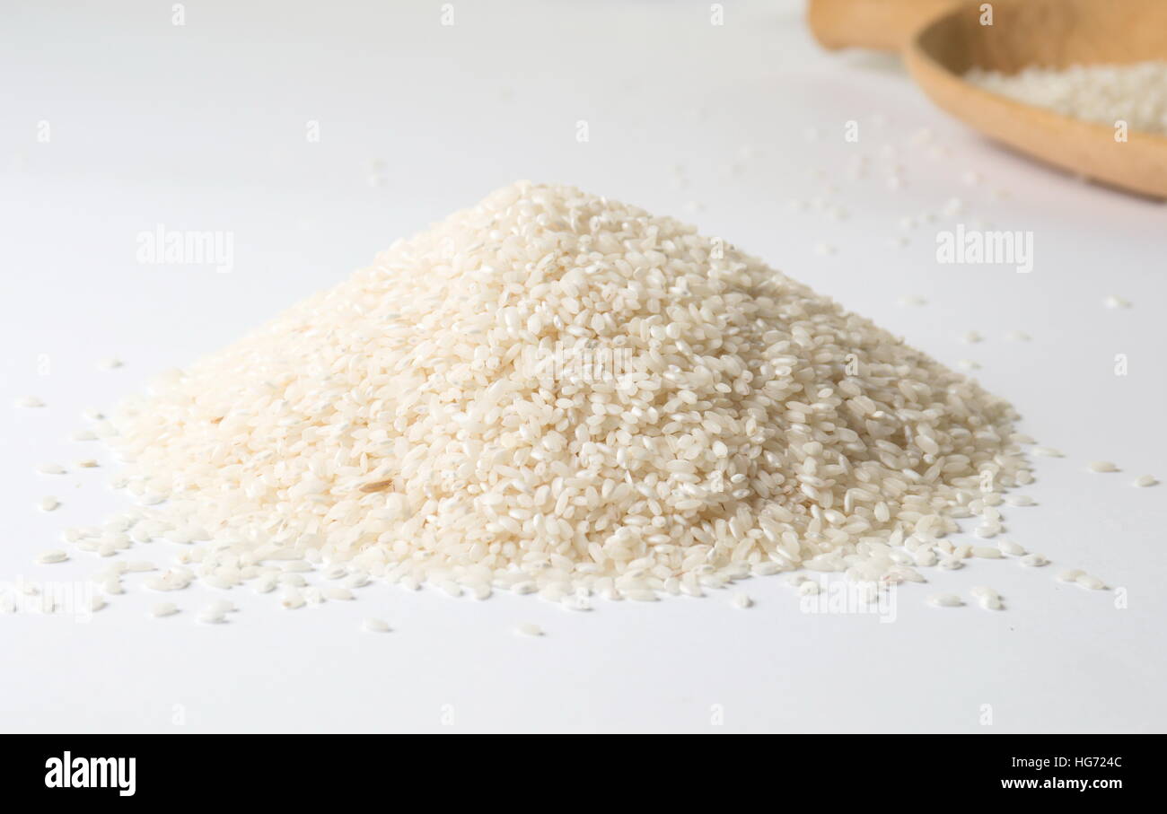 Haufen von Reis und großen Kochlöffel auf weißem Hintergrund Stockfoto