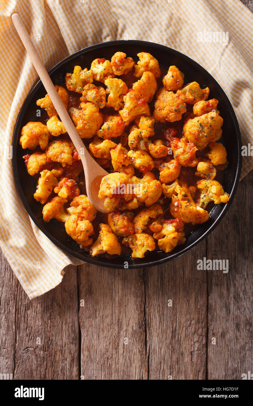 Asiatische Küche: Blumenkohl mit Tomaten in Curry-Sauce auf einem Teller. vertikale Ansicht von oben Stockfoto