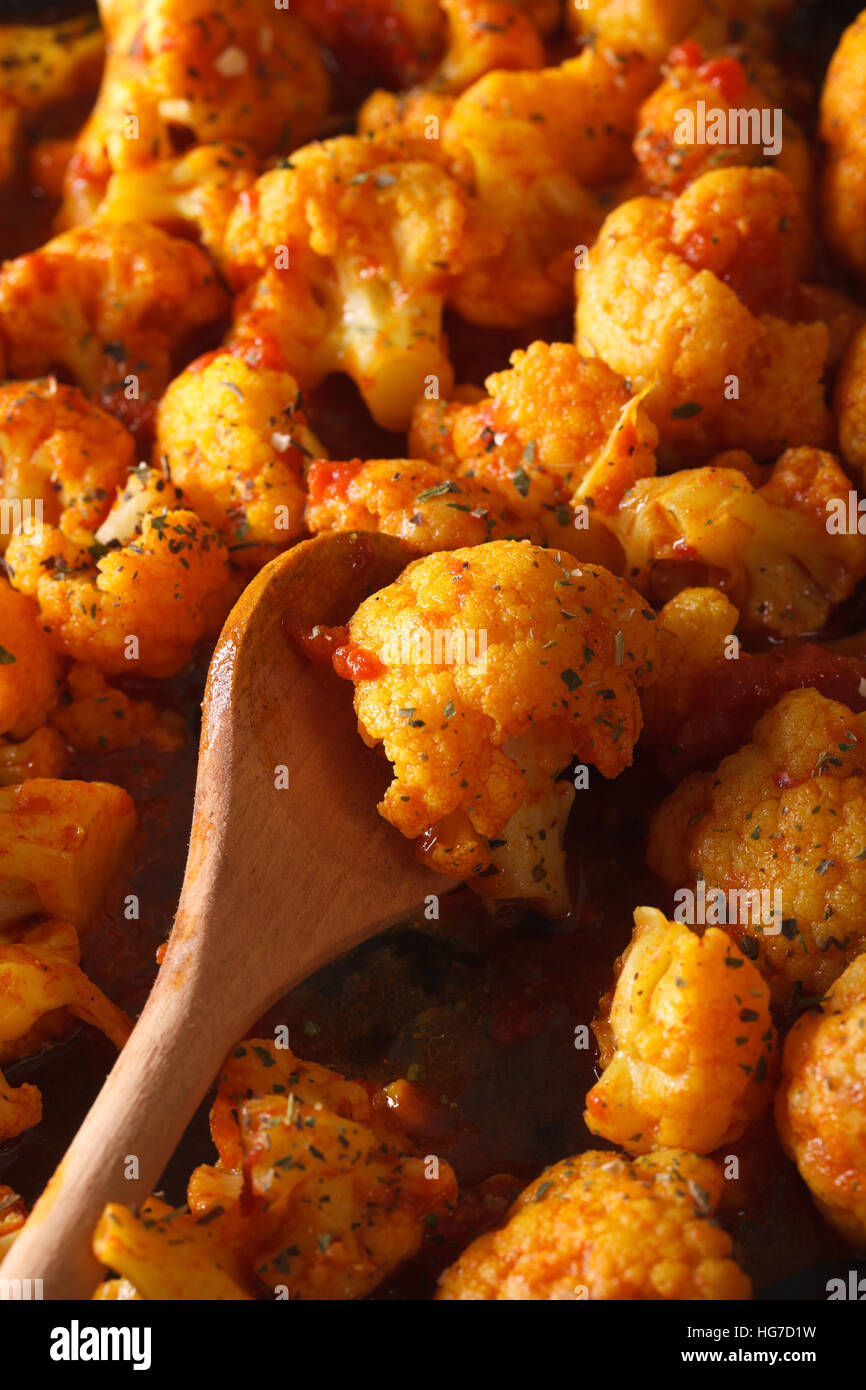 Blumenkohl mit Tomaten in Curry-Sauce-Makro. vertikale Ansicht von oben Stockfoto