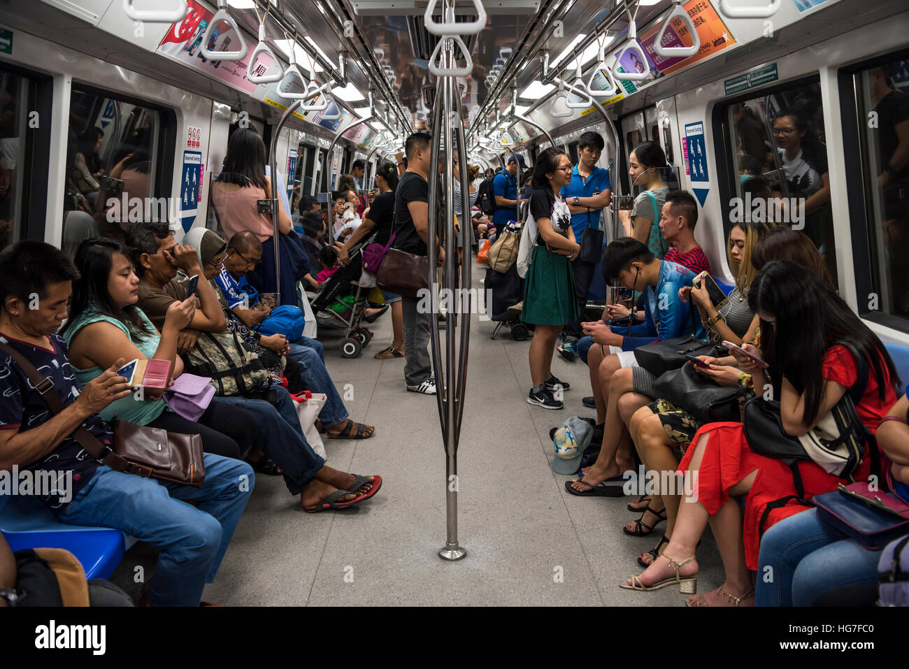 Menschen mit Smartphones auf eine MRT-Zug in Singapur Stockfoto