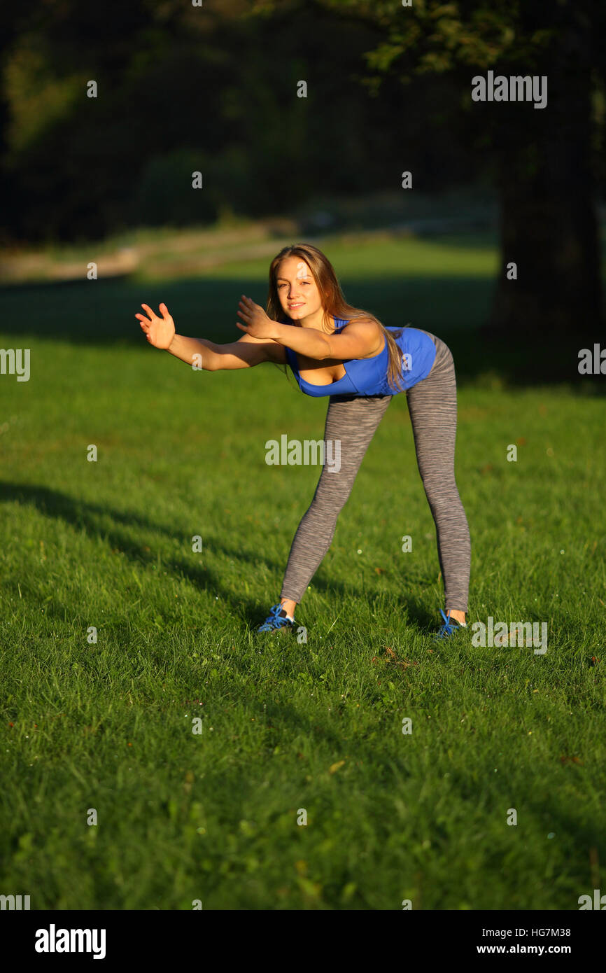 Junge Frau dabei nach vorne beugen auf Rasen Stockfoto