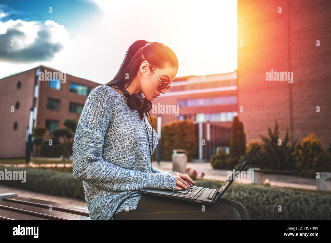Junge Frau bei outdoor, farbenfrohen Sonnenuntergang auf Laptop tippen Stockfoto