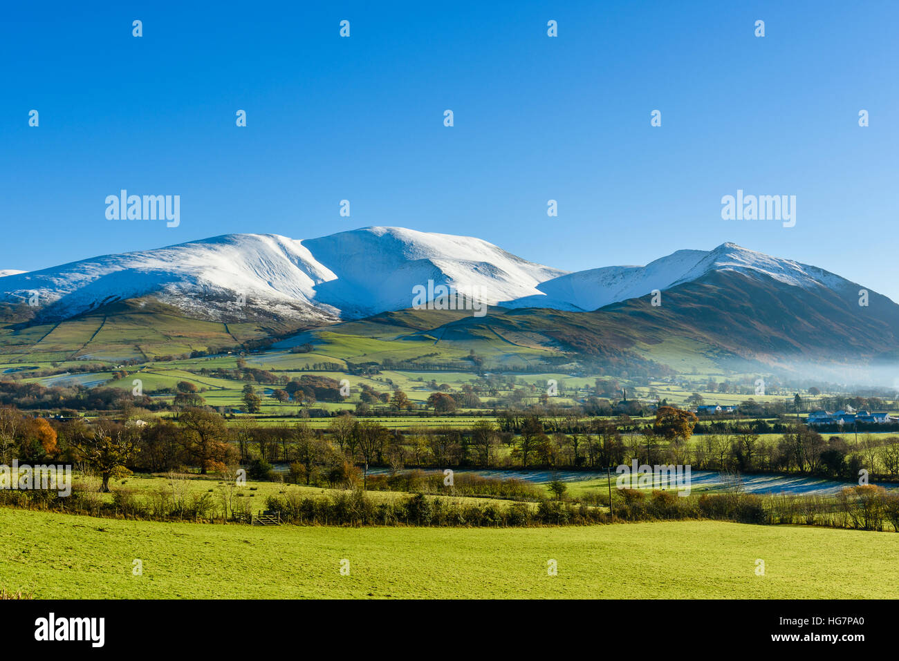 Schnee auf Skiddaw und der Ullock Hecht Kamm aus Bassenthwaite Dorf im Lake District Stockfoto