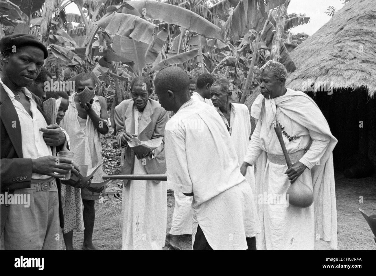 Ein afrikanischer Medizinmann (rechts) Aufsicht über die Abgabe von alkoholischen Getränken Stockfoto