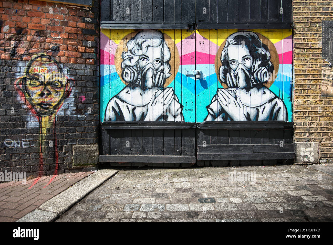 Streetart von zwei Frauen mit Spraydosen und Masken auf einem Garagentor in London Stockfoto