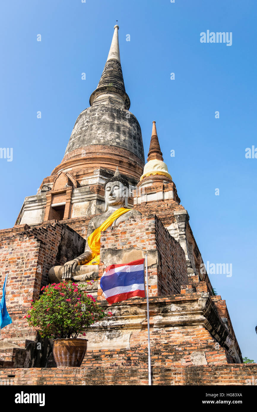 Buddha-Statue am unteren Rand eine große alte Pagode auf blauen Himmelshintergrund am Wat Yai Chai Mongkon Tempel in Phra Nakhon Si Ayutthaya Historical Stockfoto