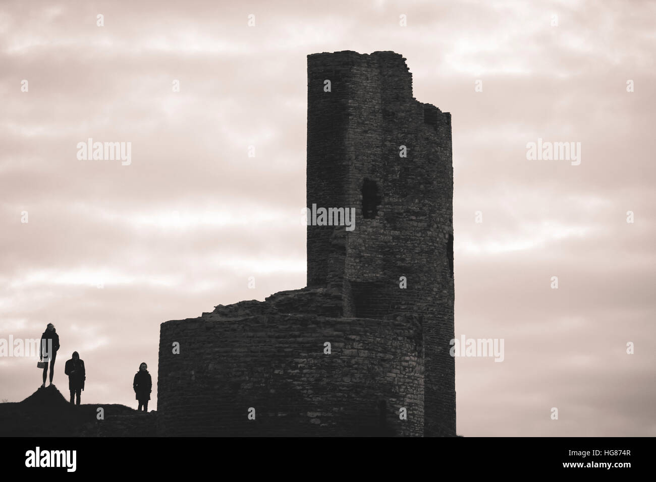 Drei Menschen Stand stehen in der Silhouette neben dem zerstörten Turm von Aberystwyth Schloss Wales UK (BHZ) Stockfoto