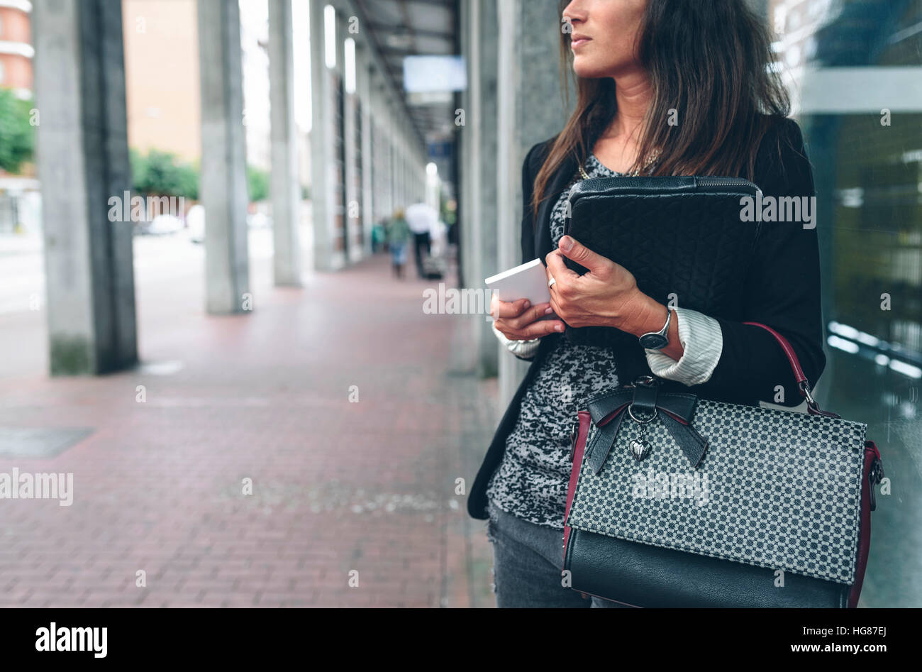 Mittelteil Frau mit Handy Geldbörse steht durch Fenster Stockfoto