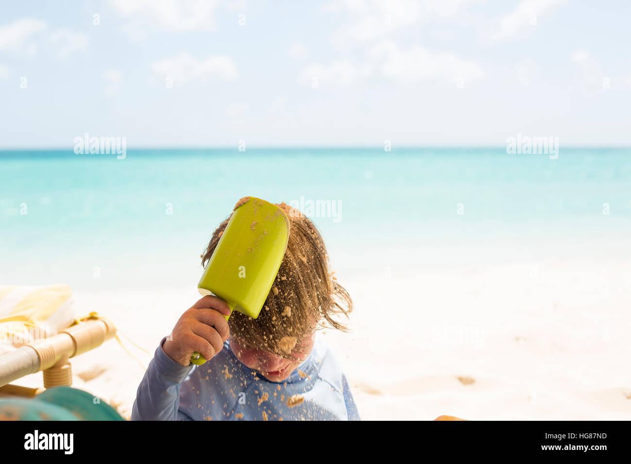 Junge strömenden Sand am Kopf mit Spielzeug Schaufel am Strand Stockfoto