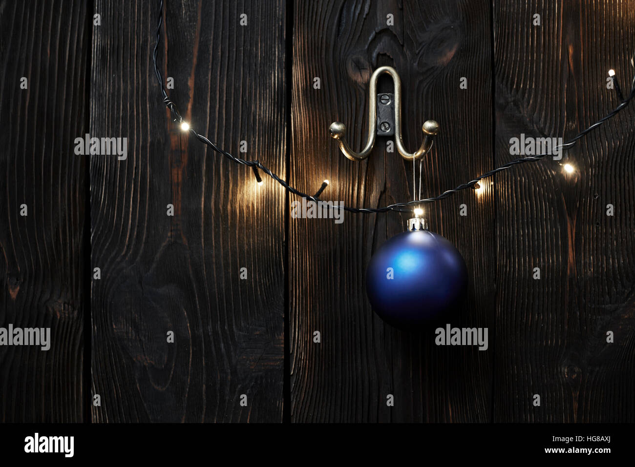 Weihnachtsbeleuchtung und Tand an Holzwand hängen Stockfoto