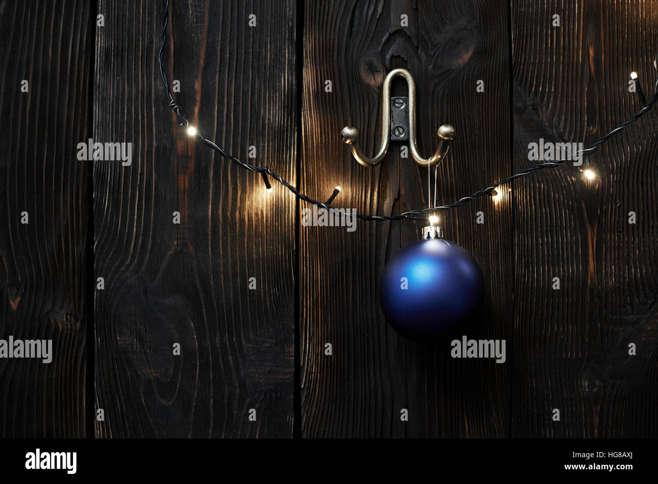 weihnachtsbeleuchtung und weihnachtskugel hängen an einer Holzwand Stockfoto
