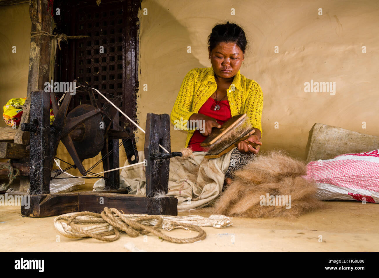 Einheimische Frau spinnt Schafwolle mit traditionellen Spinnrad vor Haus, Ghandruk, Distrikt Kaski, Nepal Stockfoto