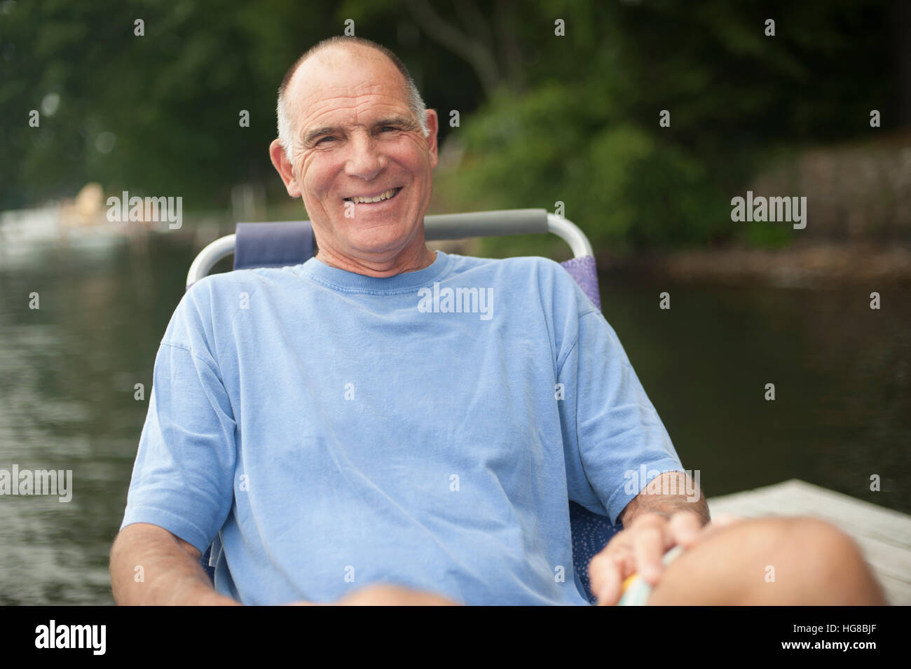 Porträt auf Liegestuhl gegen See entspannen glücklicher Mann Stockfoto