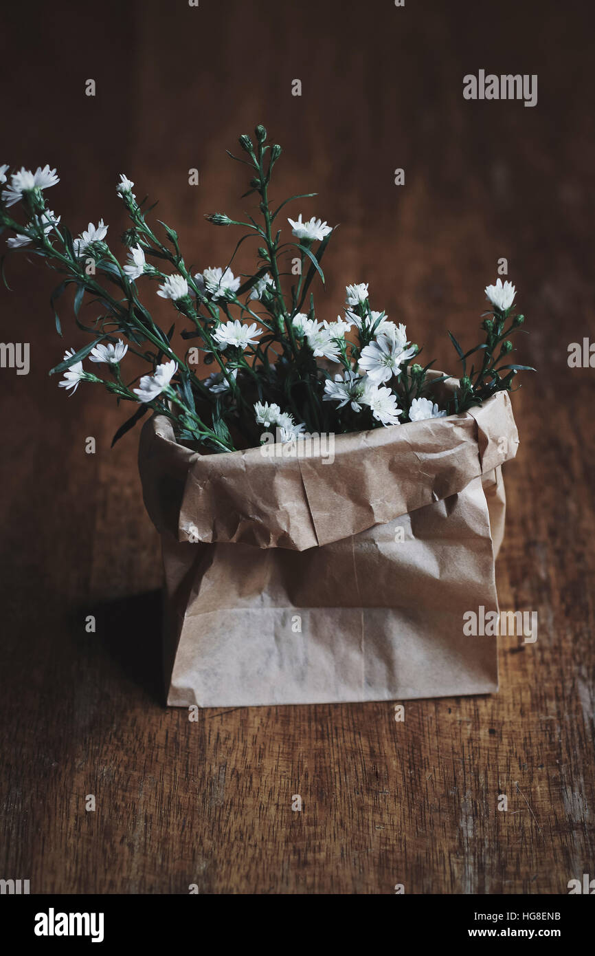 Nahaufnahme von weißen Blüten in Papiertüte auf Tisch Stockfoto