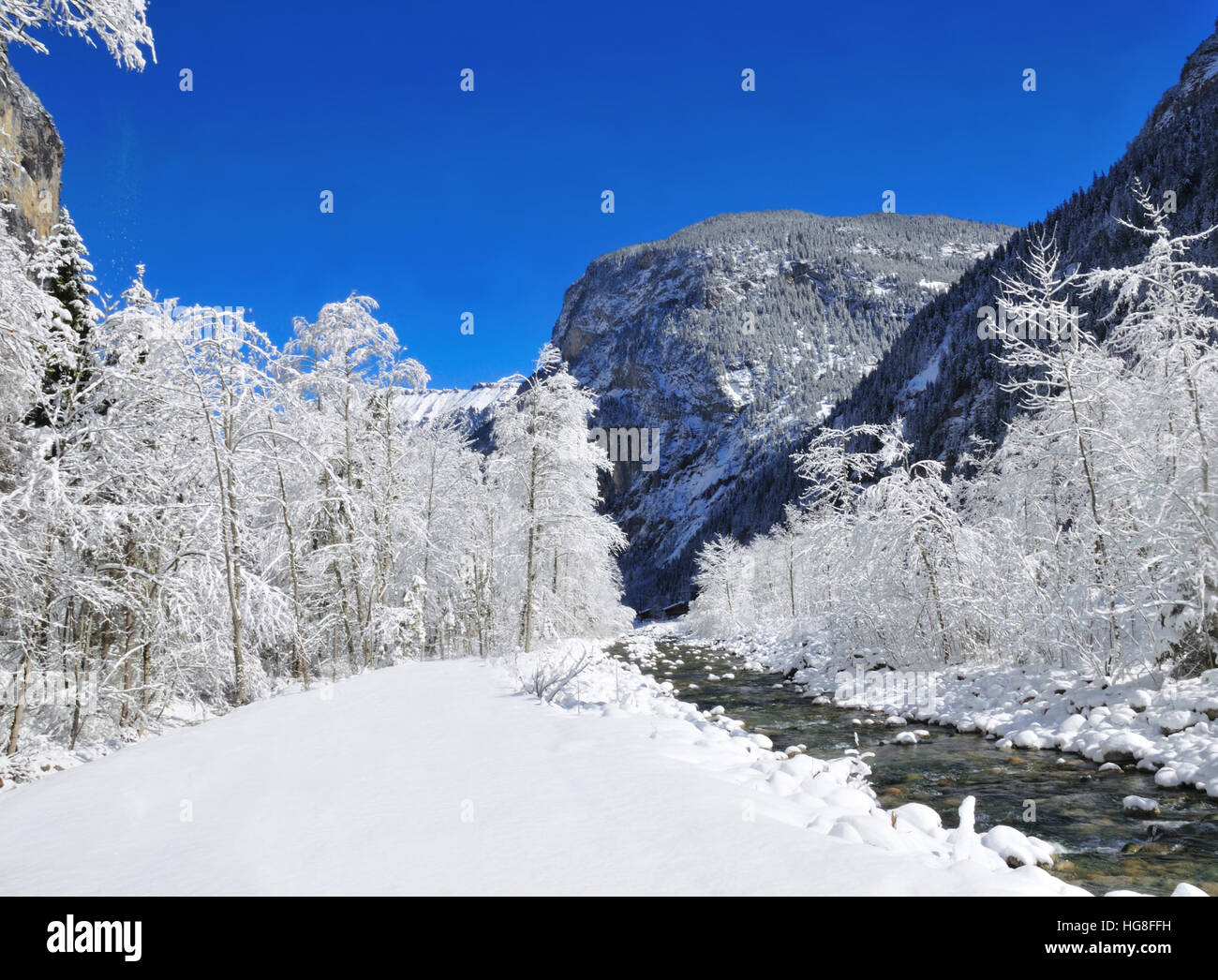 Bach im Schnee neben Wanderweg im Lauterbrunnental im schweizerischen Berner Oberland. Stockfoto