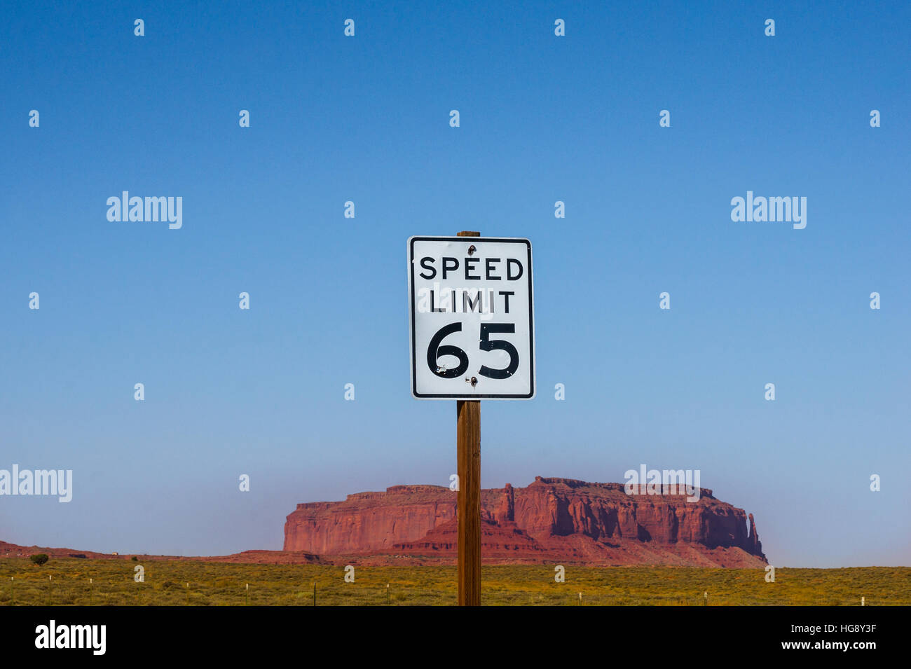 Die erlaubte Höchstgeschwindigkeit 65 - Schild mit Monument Valley Butte im Hintergrund. US amerikanische Straßenschild Stockfoto
