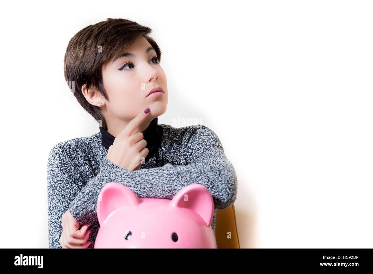 Junge Frau nachdenklich über Einsparungen bei den Sparschwein, isoliert nachschlagen auf weißem Hintergrund Kopie Raum auf der rechten Seite Stockfoto