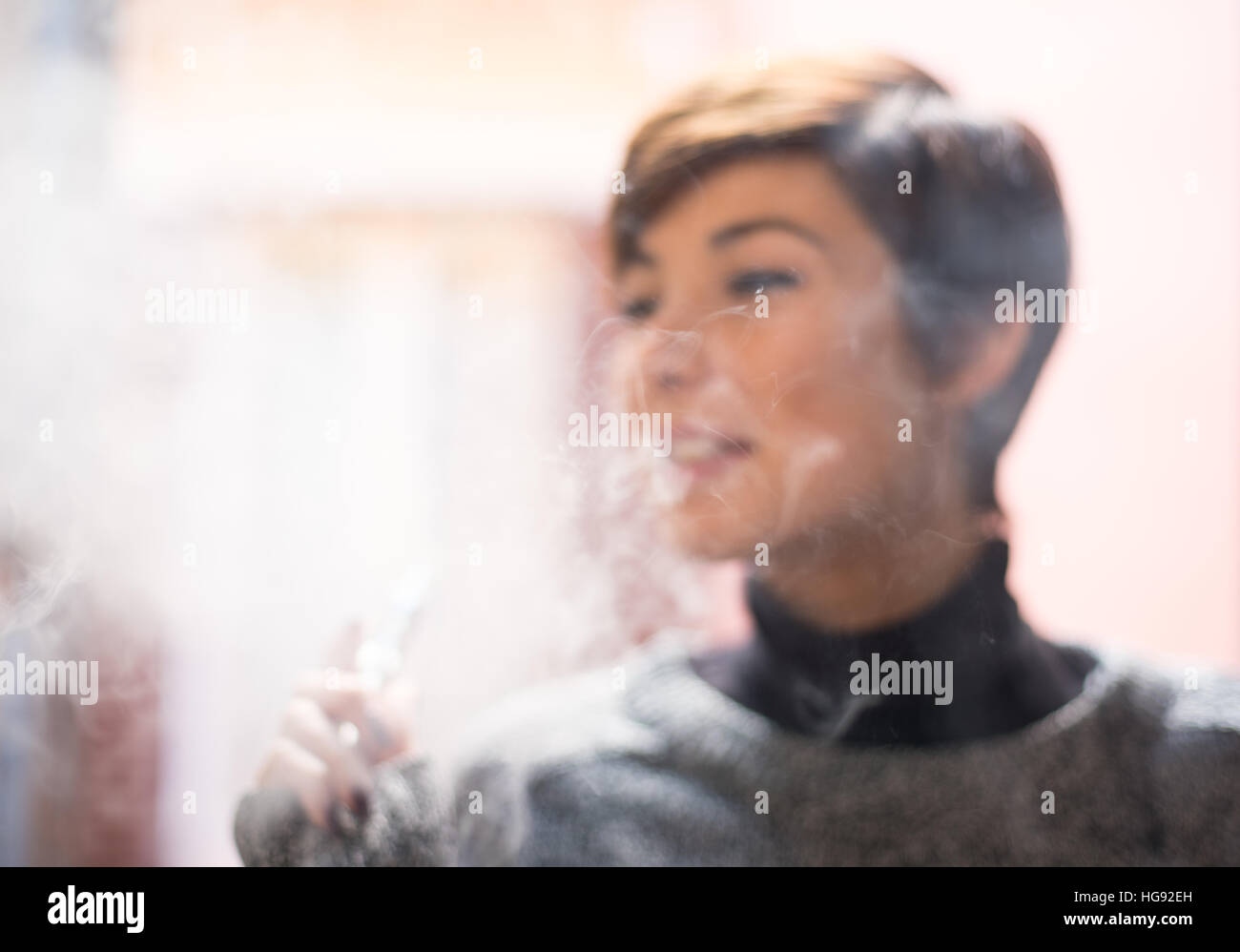 Junge hübsche Frau unscharf gestellt in eine Rauchwolke beim Rauchen elektronische Zigarette Stockfoto
