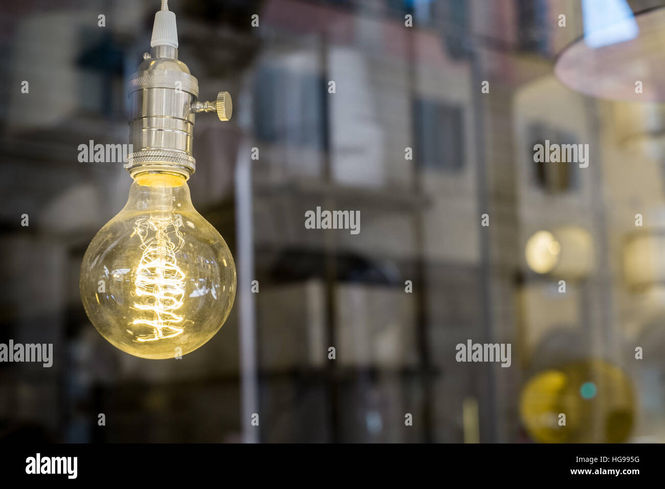 Dekorative alte Edison Stil Glühbirne gegen unscharfe Geschaeftsviertel reflektierenden Hintergrund Stockfoto