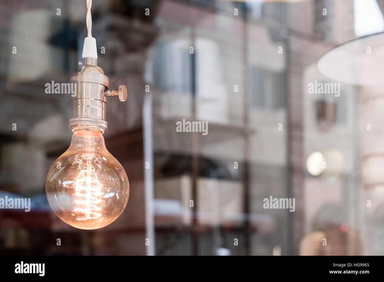 Dekorative alte Edison Stil Glühbirne gegen unscharfe Geschaeftsviertel reflektierenden Hintergrund Stockfoto