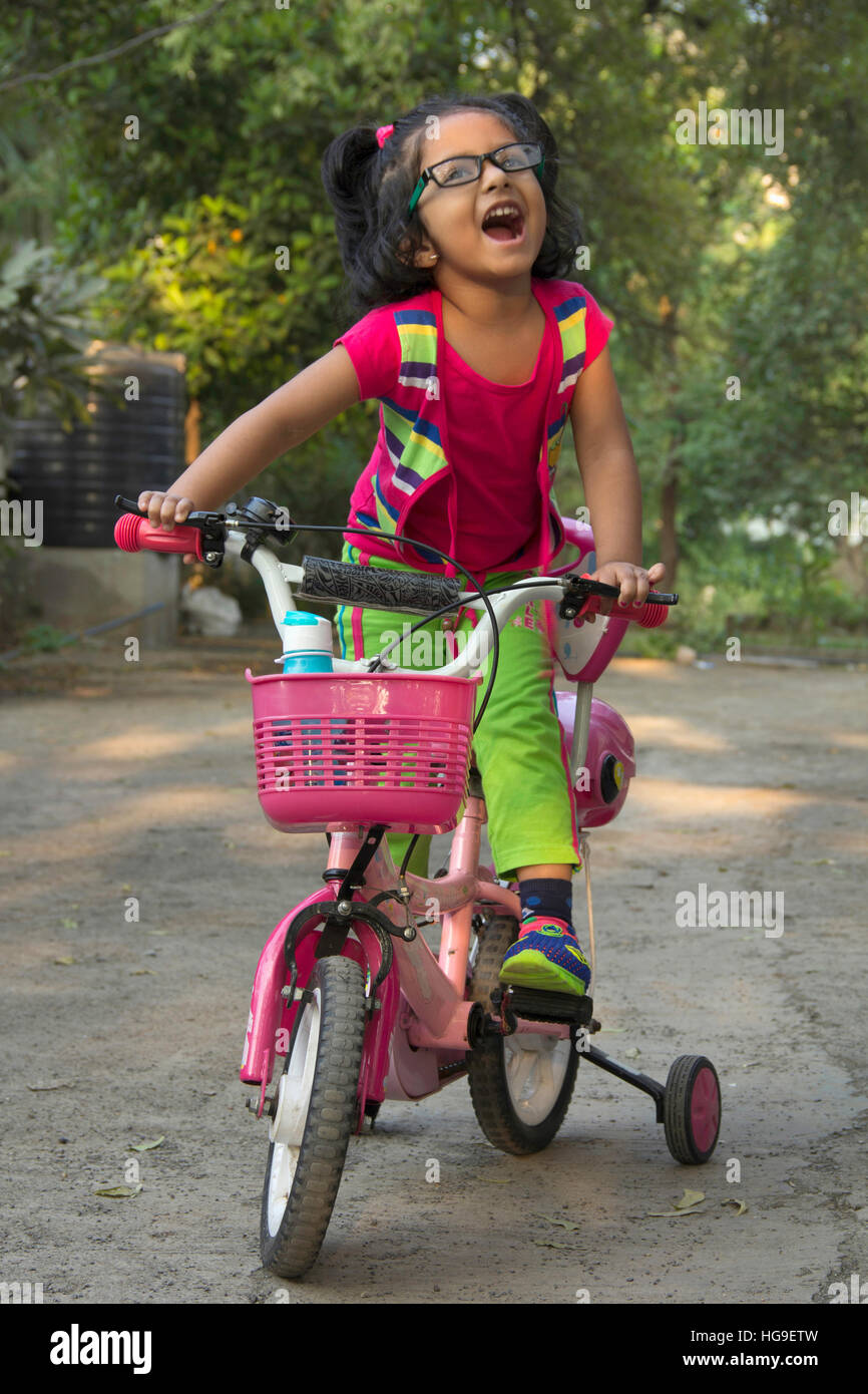 Kleine Inderin mit Specs, mit dem Fahrrad in rosa gekleidet. Stockfoto