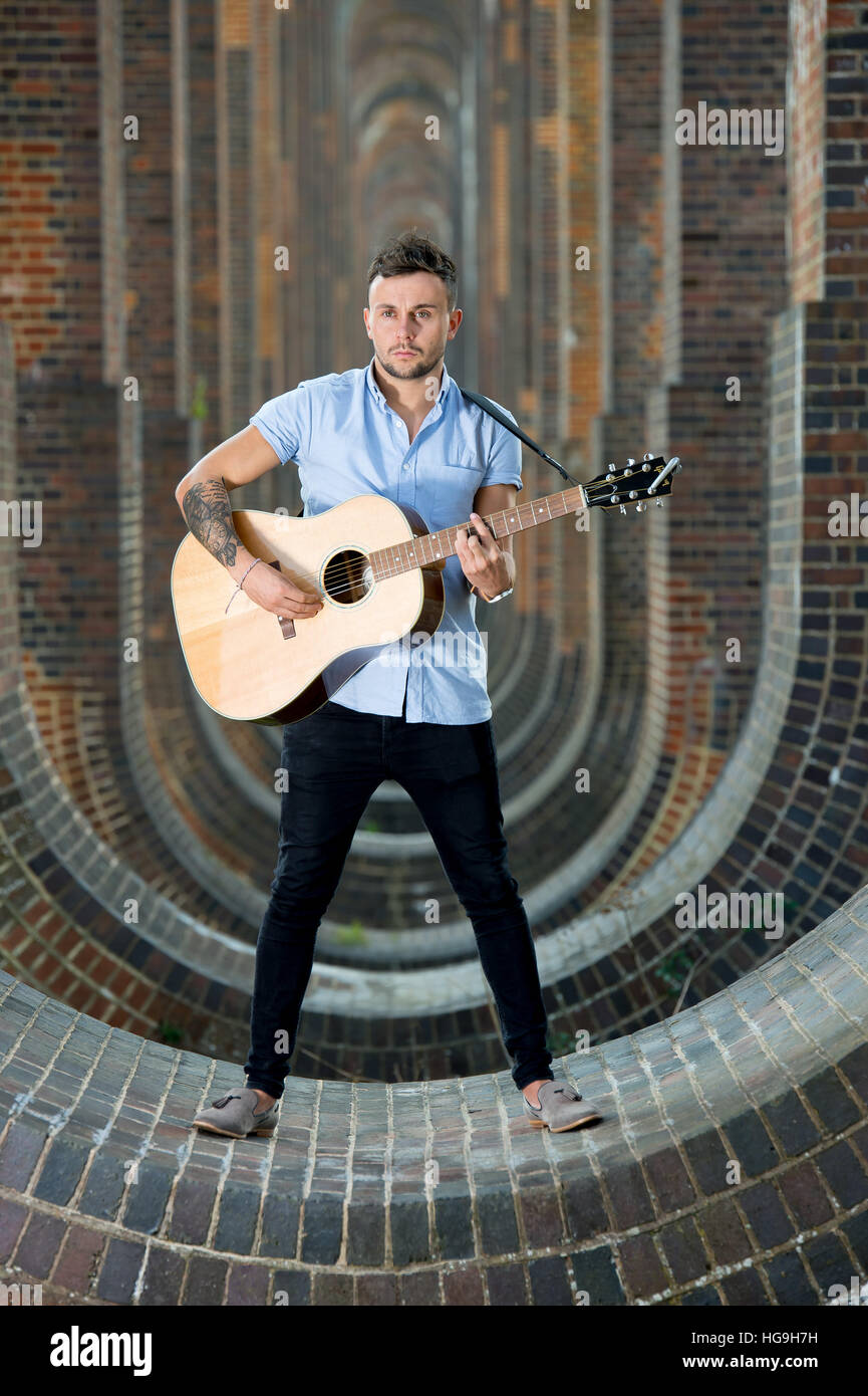 Sänger, posiert Songwriter Jamie Mathias mit seiner Gitarre für ein Shooting an der Ouse Valley-Viadukt, Sussex, UK. Stockfoto